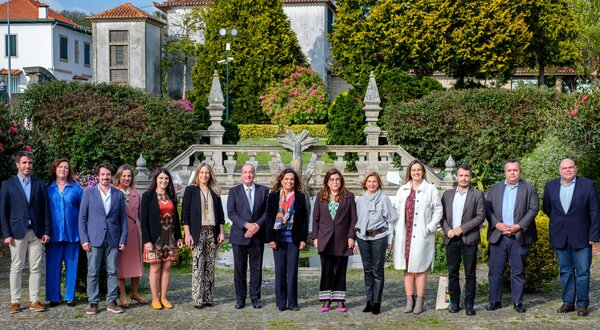 Grupo de pessoas posando em frente a um jardim com fonte decorativa.