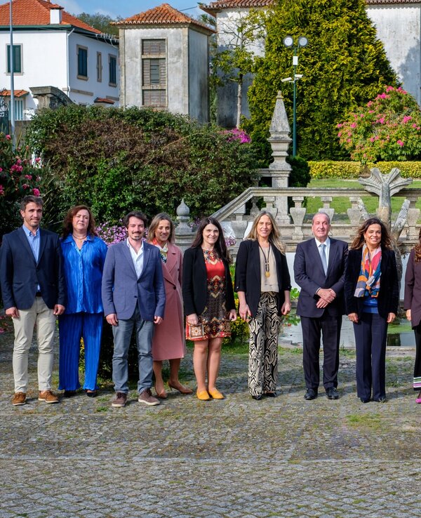 Grupo de pessoas posando em frente a um jardim com fonte decorativa.