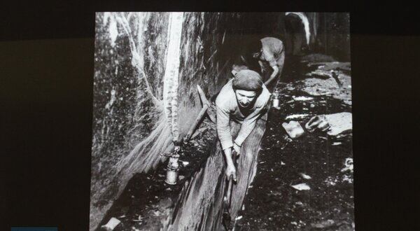 Imagem em preto e branco de trabalhadores em condições difíceis, escavando.