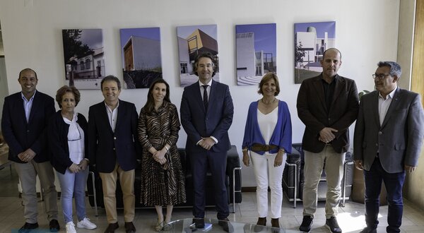 Grupo de pessoas em pé, posando em um ambiente com fotografias ao fundo.