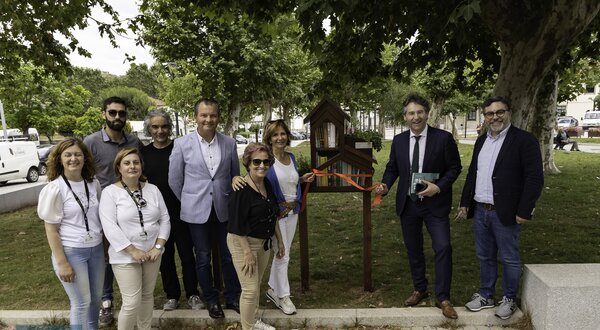 Grupo de pessoas posando junto a um pequeno abrigo para pássaros.