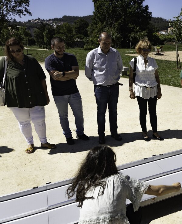 Grupo de pessoas observando uma demonstração de equipamento acessível ao ar livre.