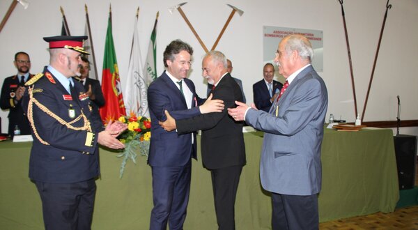 Cerimónia de entrega de prémios com várias pessoas a cumprimentar-se.