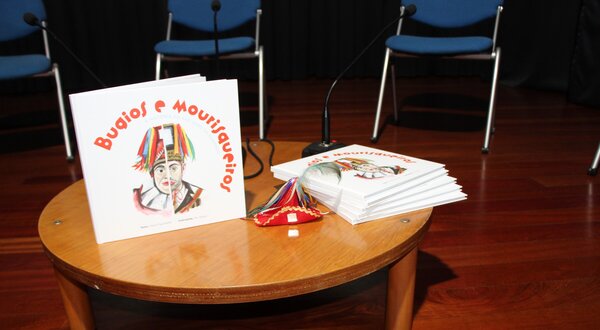 Mesa redonda com livros infantis e um pequeno objeto decorativo.