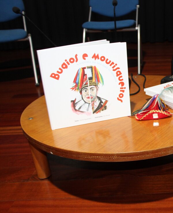 Mesa redonda com livros infantis e um pequeno objeto decorativo.