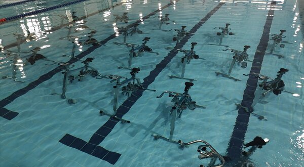 Piscina com bicicletas aquáticas dispostas em filas sobre a água.