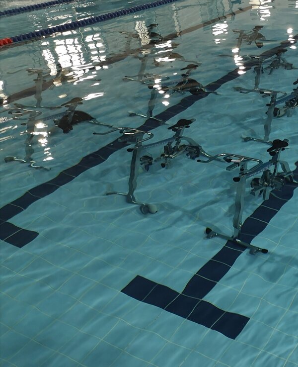 Piscina com bicicletas aquáticas dispostas em filas sobre a água.