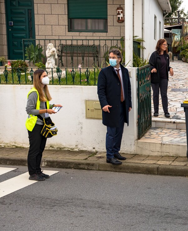 Grupo de pessoas a discutir perto de contentores de lixo em ambiente urbano.