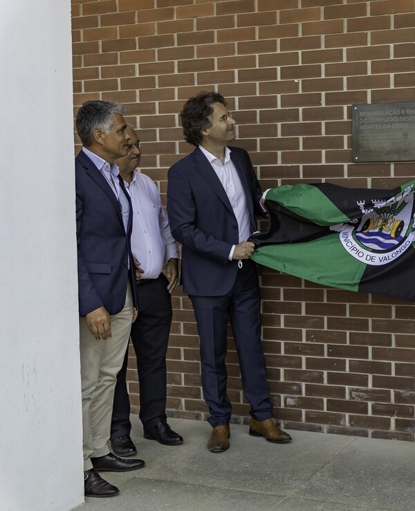 Cerimónia de descerramento de placa com uma bandeira em destaque.