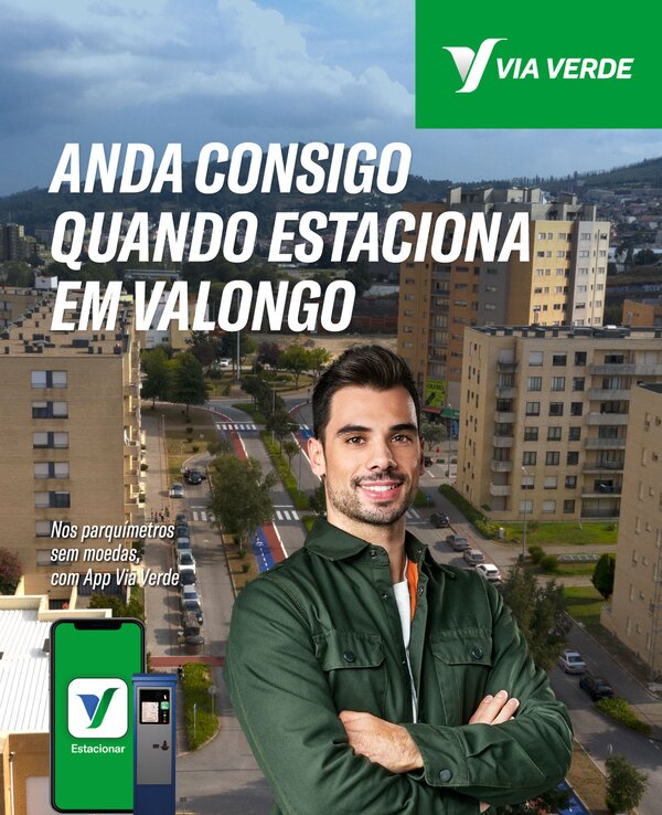 Homem de braços cruzados em frente a edifícios e parquímetros em Valongo.