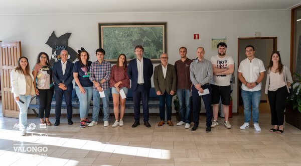 Grupo de pessoas posando em um interior, com um quadro ao fundo.
