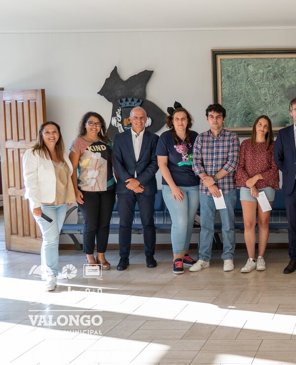 Grupo de pessoas posando em um interior, com um quadro ao fundo.