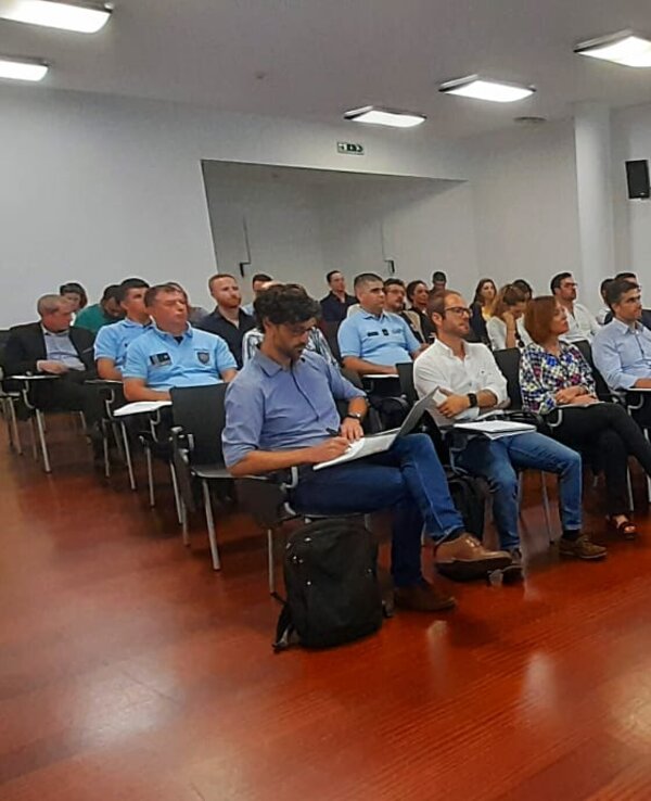 Uma sala de conferências com um orador e uma audiência atenta.