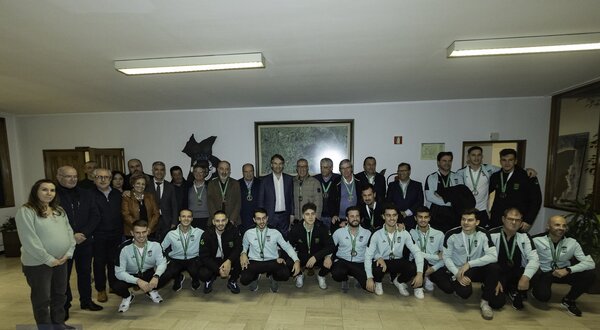 Grupo de pessoas posando em uma sala, com medalhas ao pescoço.
