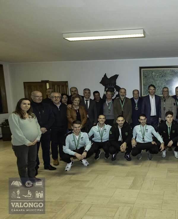 Grupo de pessoas posando em uma sala, com medalhas ao pescoço.