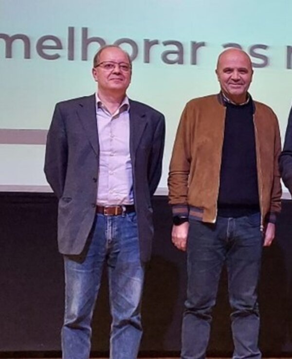 Grupo de cinco pessoas em palco, segurando um certificado de reconhecimento.