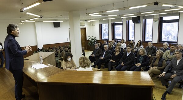 Um orador apresenta-se a uma audiência sentada em um salão amplo.