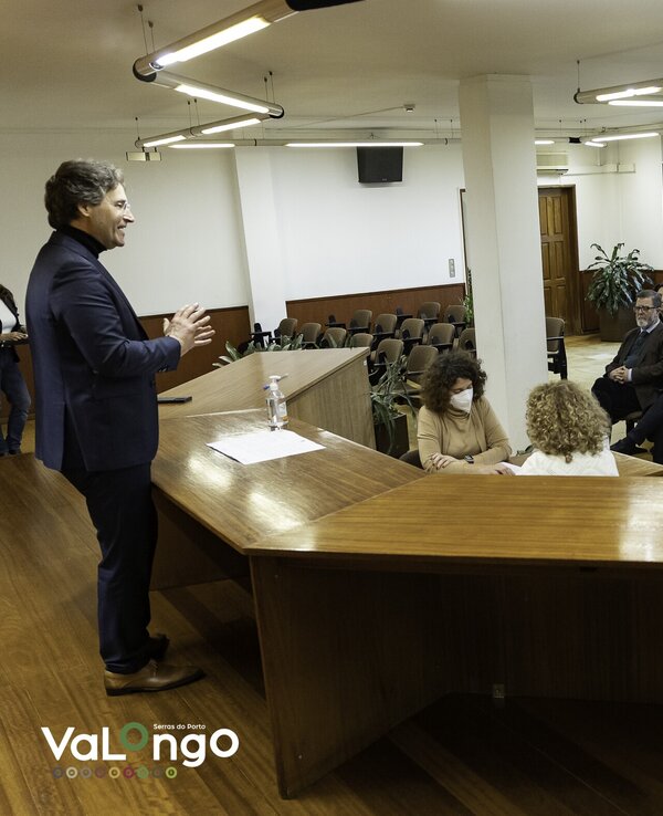 Um orador apresenta-se a uma audiência sentada em um salão amplo.