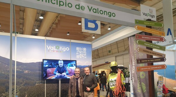 Stand do Município de Valongo com pessoas, tela e manequim de escalada.