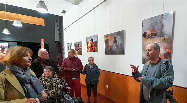 Grupo de pessoas a ouvir um guia numa galeria de arte com fotografias.