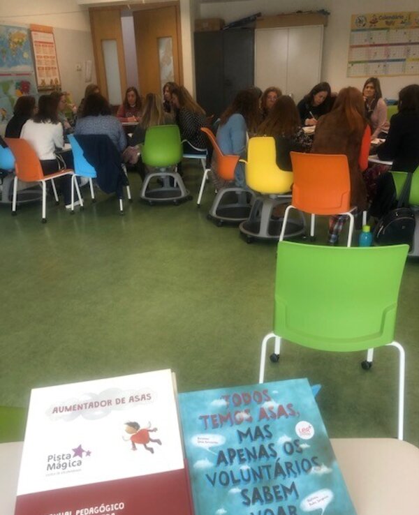 Mesa com livros sobre voluntariado e grupo de pessoas a discutir.