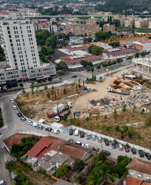 Vista aérea de um local de construção com edifícios e veículos estacionados.