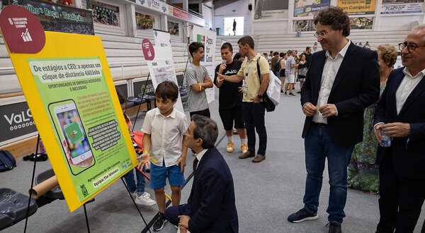 Um grupo de pessoas observa um cartaz sobre tecnologia assistiva.
