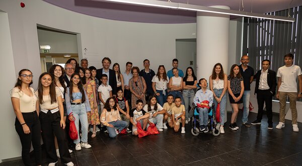 Grupo de jovens e adultos posando juntos num espaço interior moderno.