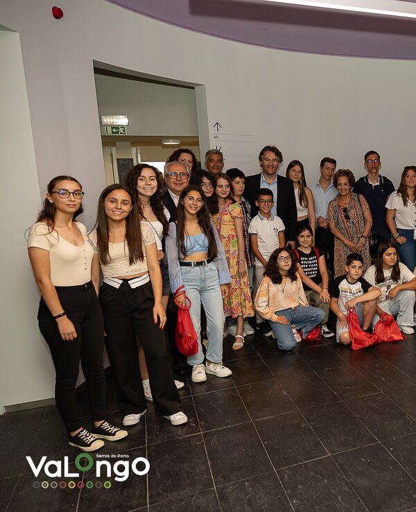 Grupo de jovens e adultos posando juntos num espaço interior moderno.