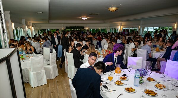 Grande sala de jantar com muitas pessoas a socializar e a comer.