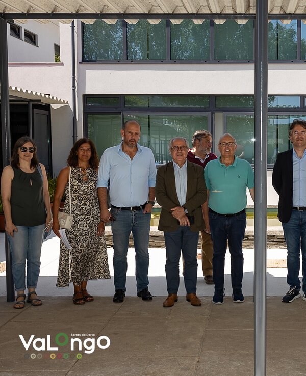 Grupo de pessoas em pé, sob uma estrutura coberta, em ambiente exterior.