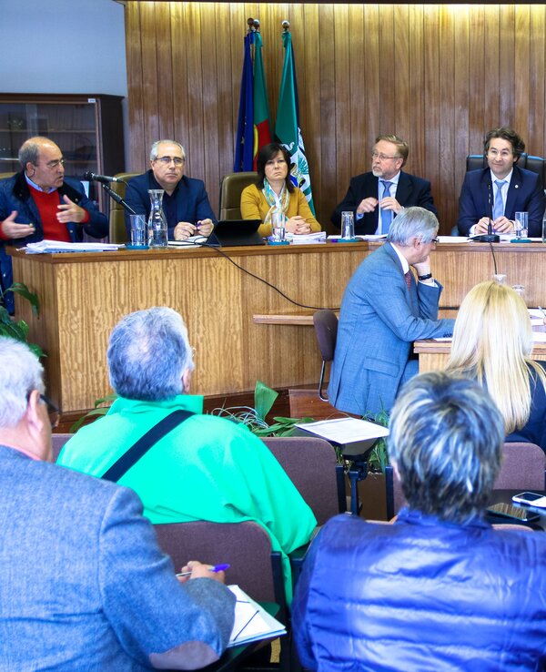Reunião com várias pessoas sentadas em mesa, discutindo assuntos importantes.