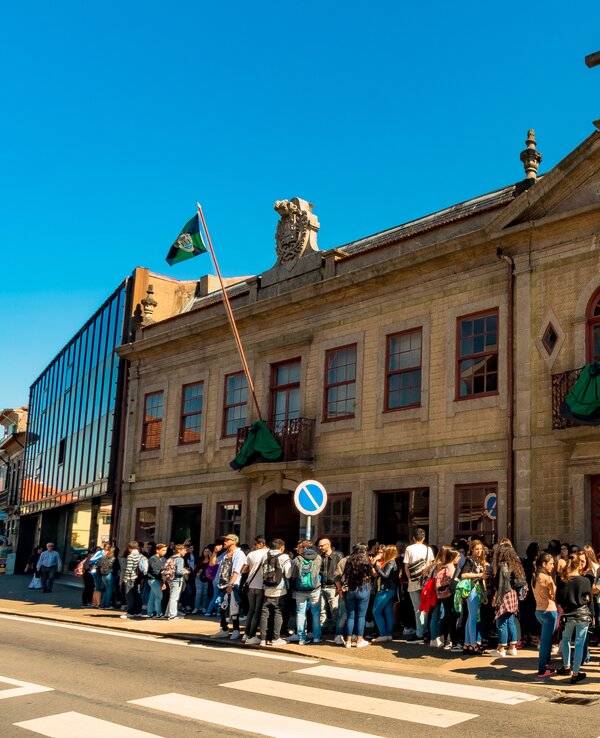 Grupo de pessoas em fila à frente de um edifício histórico em Valongo.
