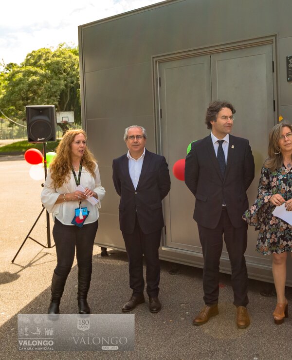 Grupo de pessoas em evento ao ar livre, junto a um quiosque metálico.