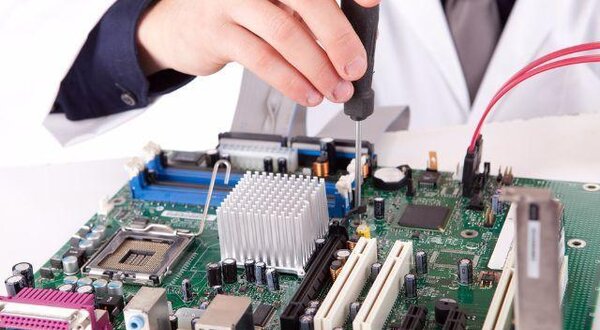 Técnico a trabalhar numa placa-mãe com uma chave de fendas.