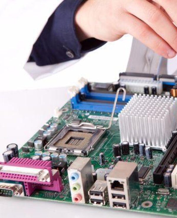 Técnico a trabalhar numa placa-mãe com uma chave de fendas.