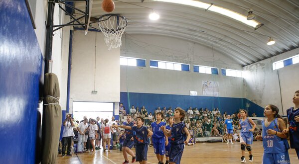 Crianças a jogar basquetebol, com uma bola a entrar na cesta.