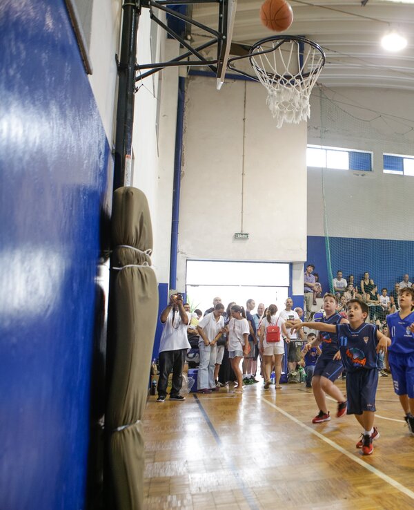 Crianças a jogar basquetebol, com uma bola a entrar na cesta.