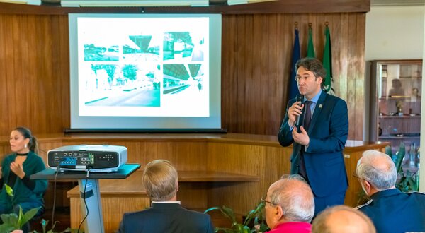 Um orador apresenta um projeto, com imagens projetadas atrás dele.