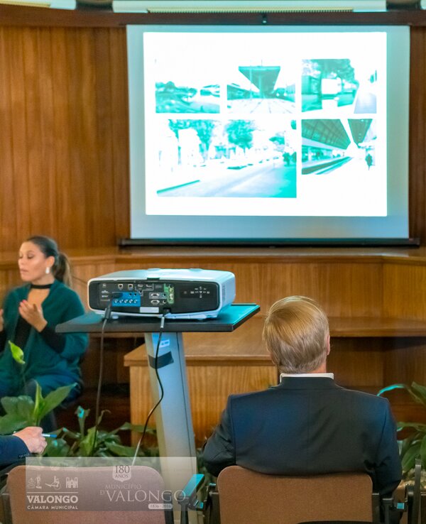 Um orador apresenta um projeto, com imagens projetadas atrás dele.