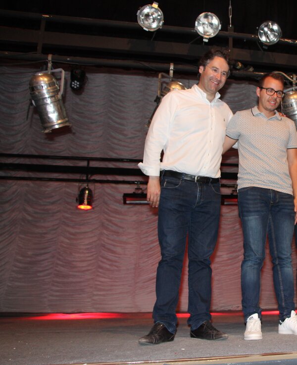 Quatro homens em palco, vestidos de forma casual, com luzes ao fundo.