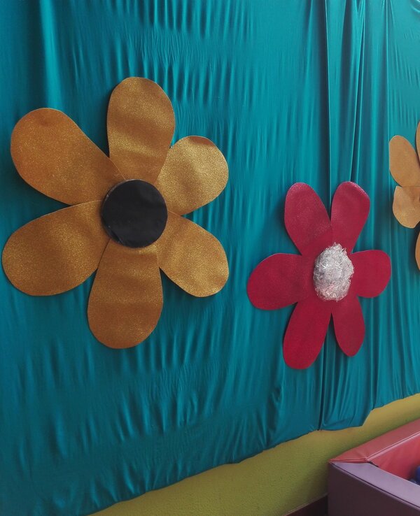 Paredes decoradas com flores grandes e coloridas, ao lado de uma piscina de bolas.