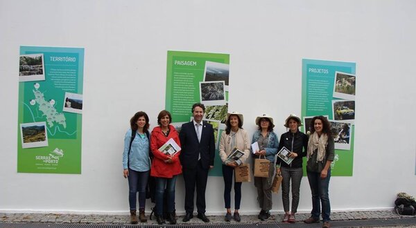 Grupo de pessoas sorridentes em frente a painéis informativos sobre a Serra.