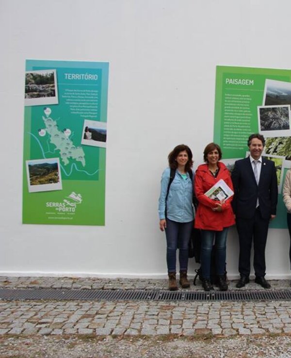 Grupo de pessoas sorridentes em frente a painéis informativos sobre a Serra.