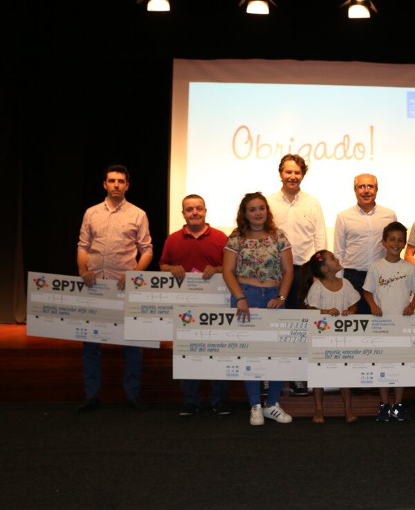 Grupo de pessoas a segurar grandes cheques em evento de agradecimento.