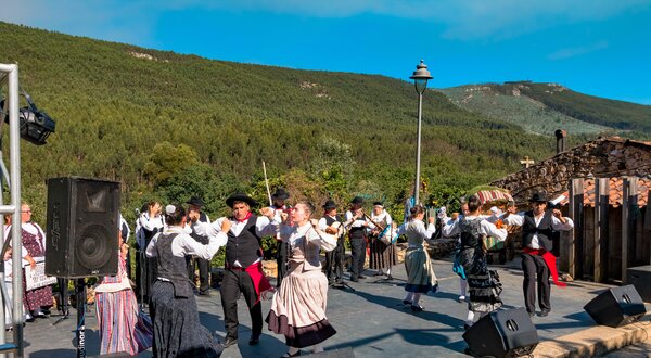 Grupo de dançarinos em trajes tradicionais a dançar ao ar livre.