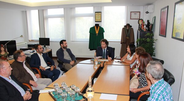 Reunião em sala com várias pessoas sentadas à volta de uma mesa.