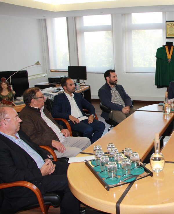 Reunião em sala com várias pessoas sentadas à volta de uma mesa.