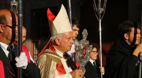 Um líder religioso em vestes cerimoniais, segurando um objeto sagrado.
