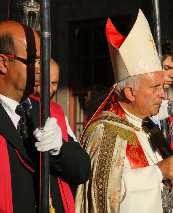 Um líder religioso em vestes cerimoniais, segurando um objeto sagrado.